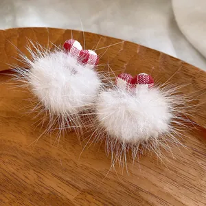 Detailed macro view of sweet heart fur pom-pom earrings on a rustic wooden texture tray