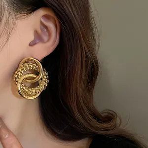 Detailed close-up view of elegant golden knotted round stud earrings on a model
