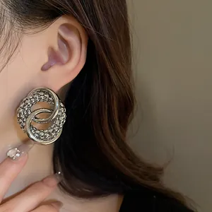 Close-up shot of a silver knot stud earring worn by a model, showing detailed metal texture.