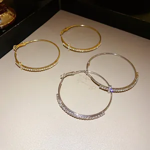 Detailed view of silver needle hoop earrings with cross and diamond-like stones