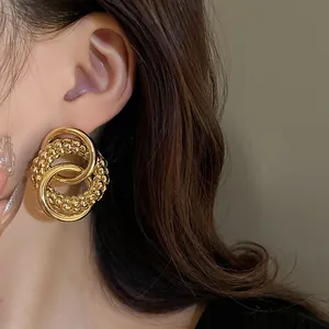 Detail shot of gold knotted hoop earrings with textured bead design worn by a model