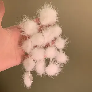 Close-up detail of soft white fur pom-pom dangling earrings with delicate pearls