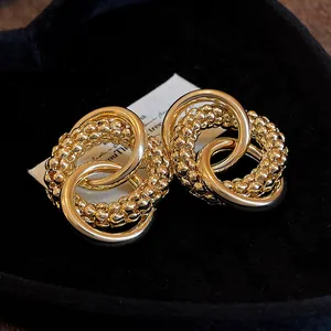 Detailed macro view of gold knotted earrings featuring smooth and beaded interlocking rings.