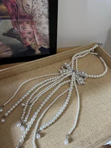 Close-up of French vintage pearl necklace with rhinestone bow on woven tray
