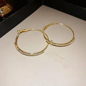 Detailed close-up view of elegant golden rhinestone-studded hoop earrings with cross design