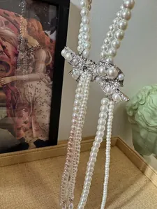 Close-up of elegant French style pearl necklace with a sparkling rhinestone bow detail.
