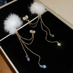 Detail view of long bow hairball earrings with sparkling crystal teardrops