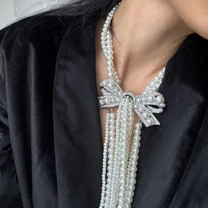 Detailed macro view of an elegant French rhinestone bow and multi-strand pearl necklace.