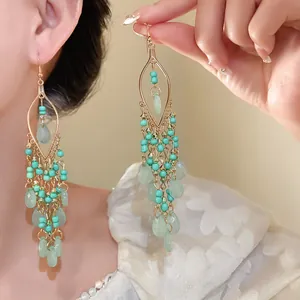 Close-up of Bohemian chandelier earrings with turquoise beads and green water-drop pendants