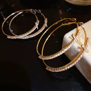 Detail view showing the sparkling cross design and rhinestone inlay on gold hoop earrings.