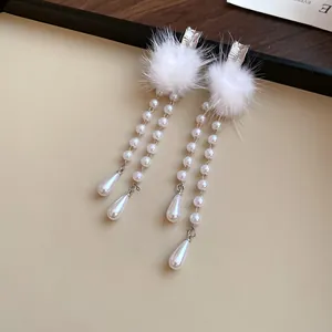 Close-up detail of elegant white faux fur ball earrings with dangling pearl bead chains.