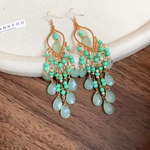 Macro view of bohemian earrings with green acrylic beads and faceted teardrops