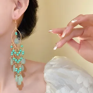 Close-up detail of Bohemian style green seed bead teardrop tassel earrings on model