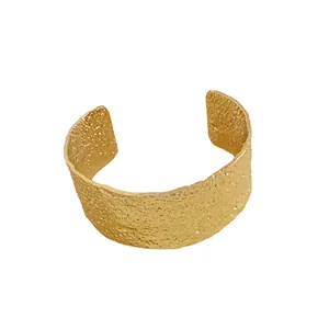Textured gold-colored metal open cuff bracelet with a creative hammered finish design.