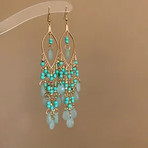 Detailed view of bohemian teardrop earrings with turquoise beads and pale green charms.
