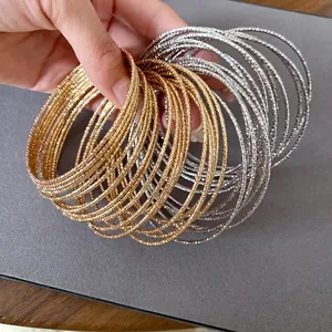 Set getextureerde goud- en zilverkleurige metalen armbanden met patronen.