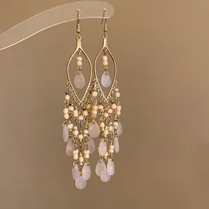 Detail view of bohemian chandelier earrings with peach beads and teardrop crystals.