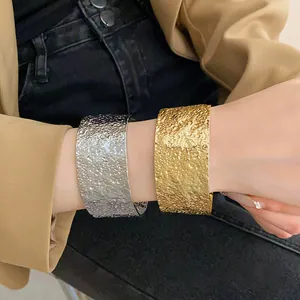 Close-up of gold and silver hammered metal open cuff bracelets on wrist