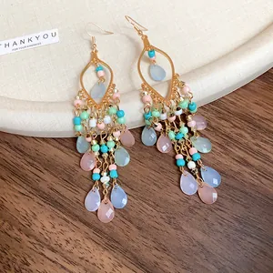 Detailed view of colorful bohemian drop earrings with tiered acrylic beads and charms.