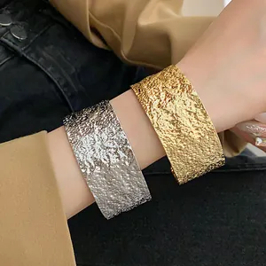 Detailed macro shot of textured gold and silver metal open cuff bracelets