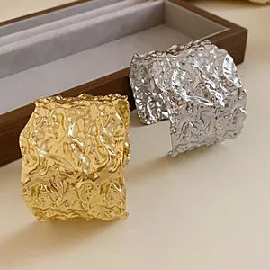 Close-up of textured gold and silver metal cuff bracelets with irregular lava effect