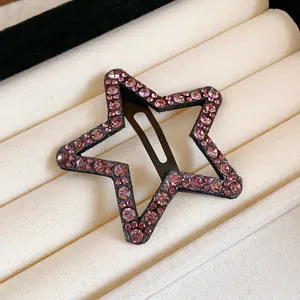 Macro detail of a star hair clip featuring sparkling pink rhinestones in a display box