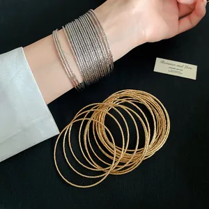 Detailopname van getextureerde metalen armbanden in goud en zilver op een pols model