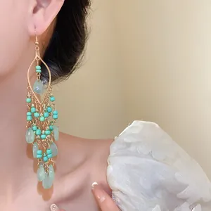Close-up view of bohemian ethnic acrylic seed bead water-drop earrings worn on a model's ear.
