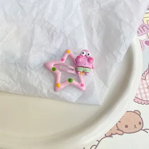 Close-up of pink star-shaped hair clip with Patrick Star cartoon character on white paper