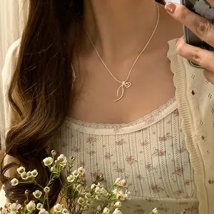 Collier pendentif délicat avec ruban argenté porté par un mannequin pour un look chic
