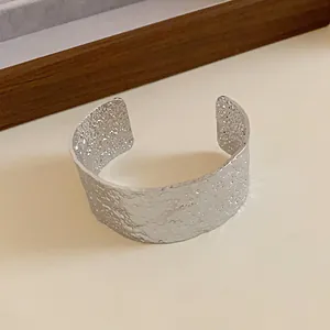 Close-up macro view of minimalist silver metal cuff bracelet with artistic hammered texture