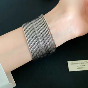 Macro-detailweergave van elegante gestapelde zilveren metalen armbanden met textuur op de pols