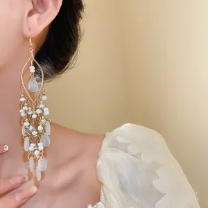 Close-up of bohemian acrylic rice bead teardrop chandelier earrings on model