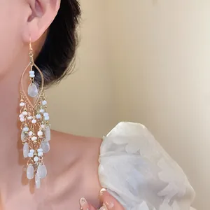 Close-up of Bohemian tassel earrings with white seed beads and teardrop pendants on model