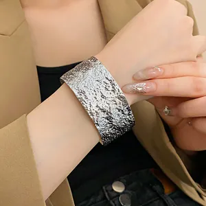 Close-up of a silver hammered texture metallic open cuff bracelet on wrist.