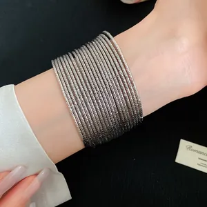 Detailweergave van zilverkleurige gestructureerde metalen armbanden om de pols van een vrouw