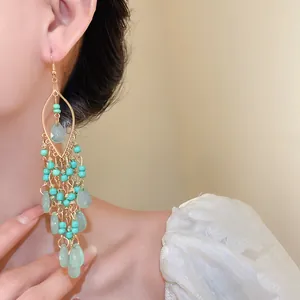 Close-up of bohemian beaded drop earrings with light green waterdrop acrylic pendants.