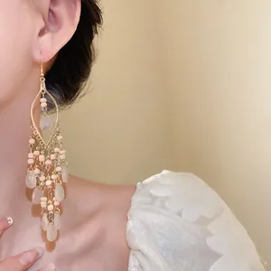 Close-up of Bohemian long tassel earrings with beige rice beads and teardrop pendants