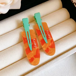 Macro view of the orange marbled texture and mint green base of these chic hair clips