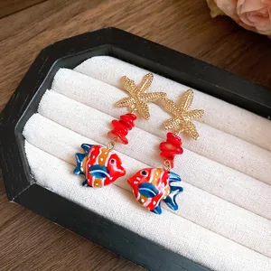 Close-up of tropical starfish and colorful glass fish drop earrings in jewelry box