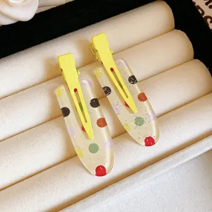 Detailed view of two colorful polka dot resin hair clips with glitter in a jewelry tray