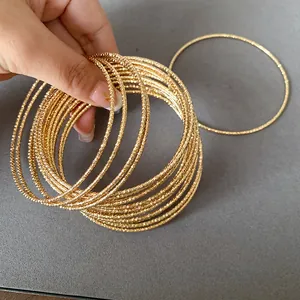Close-up van gouden metalen armbanden met getextureerde patronen in de hand.
