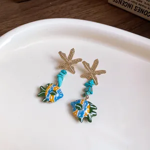 Detailed close-up of starfish and blue glass fish drop earrings with turquoise stone beads