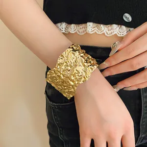 Detailed view of wide golden cuff bracelet with irregular crumpled texture