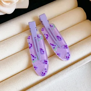 Close-up of purple dopamine flower hair clips with glitter in a jewelry display tray