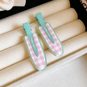 Close-up of pink and white checkered duckbill hair clips on a jewelry tray