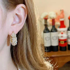 Donna indossa eleganti orecchini a cerchio placcati oro 14K con delicati fiori di perle bianche