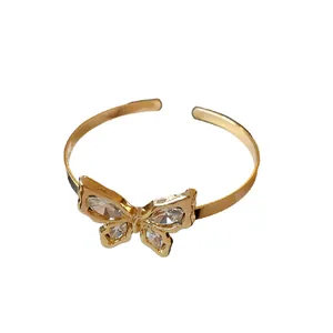 Elegant gold-plated open bangle bracelet featuring a sparkling studded butterfly motif.