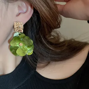 Detailed macro view showing an elegant green acrylic flower earring on a model's ear