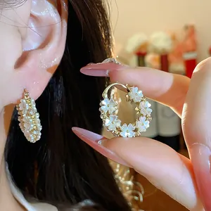 Dettaglio ravvicinato di eleganti orecchini a cerchio con fiori e perle placcati oro 14K